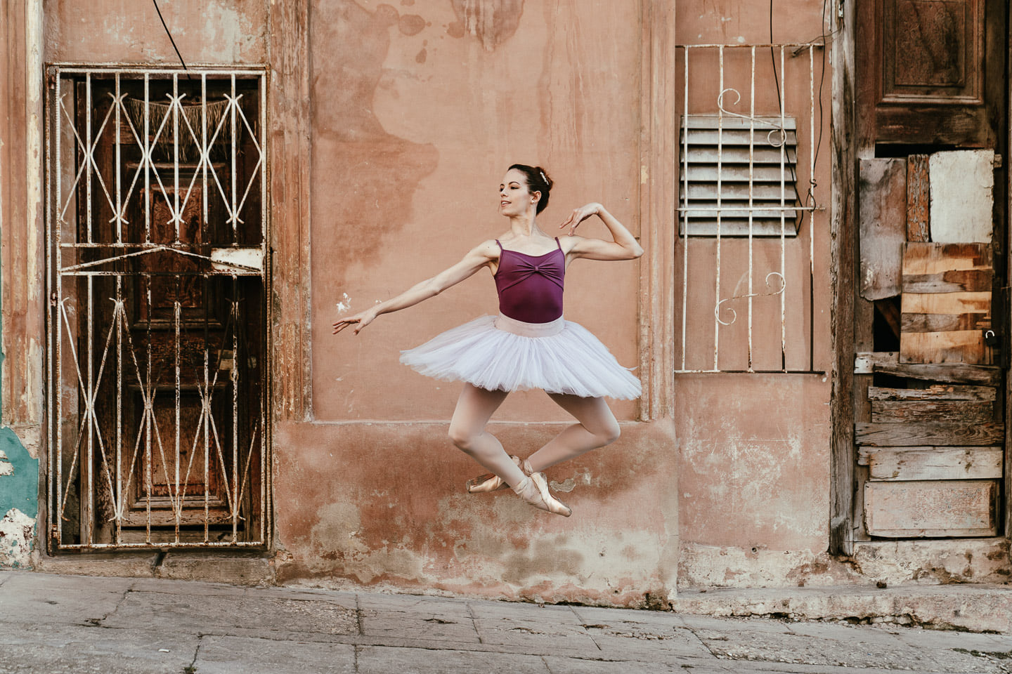 Eine professionelle Balletttänzerin springt in die Luft und verzaubert eine ganze Straße mit ihren eleganten und filigranen Bewegungen.